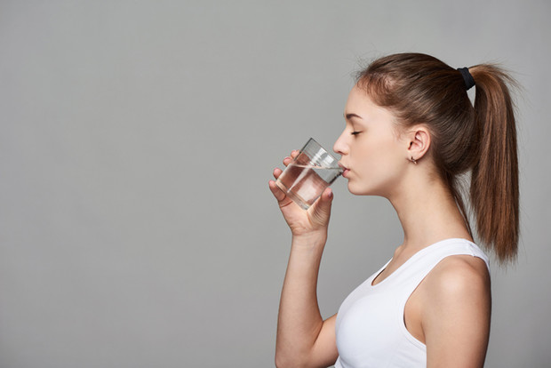 Mujer joven bebiendo agua antes de entrenar