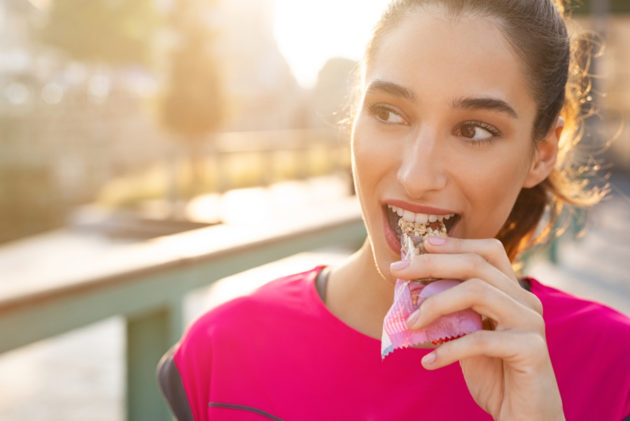 Mujer joven probando su snack de cereal antes de entrenar.